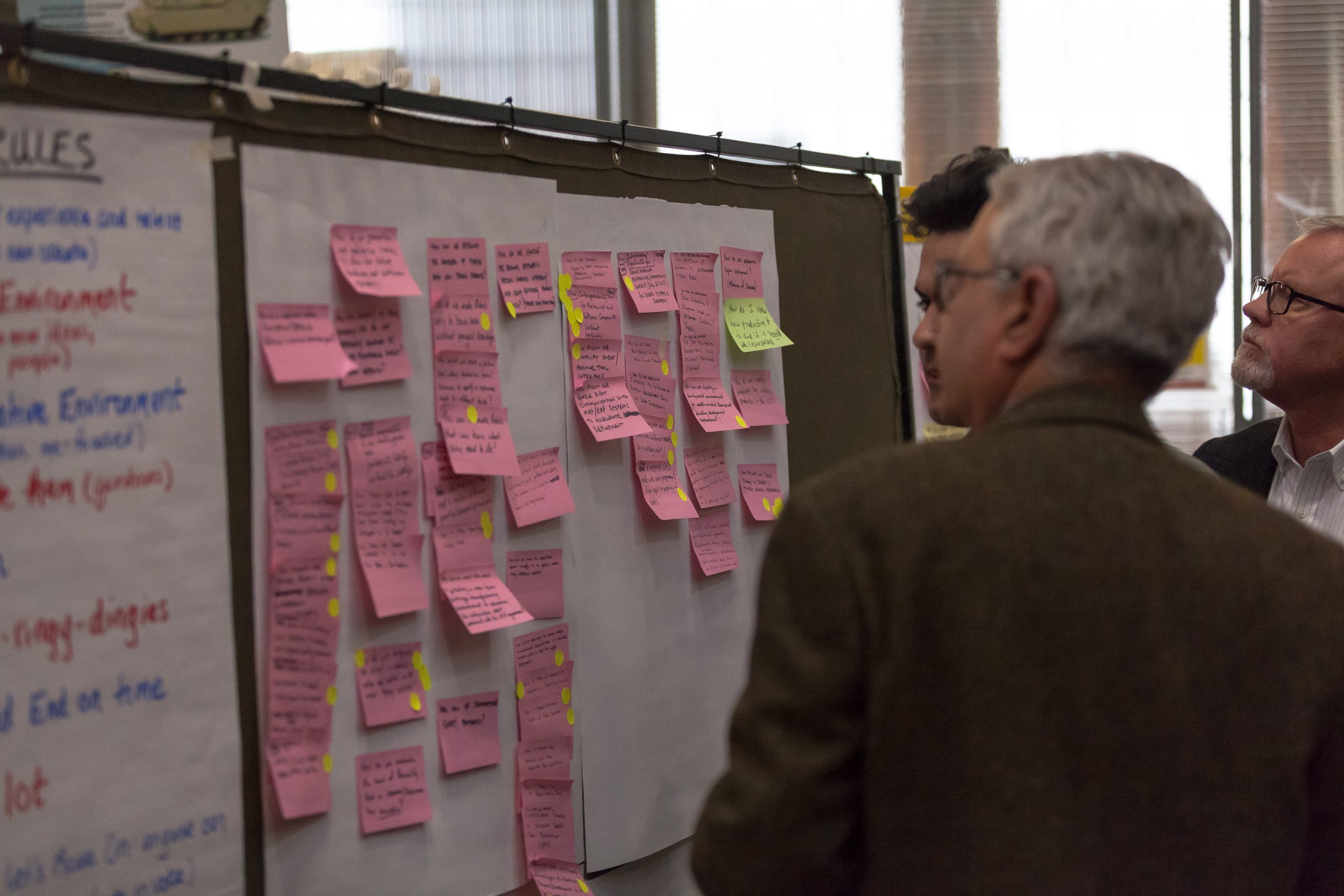 People standing by a board with post-it notes