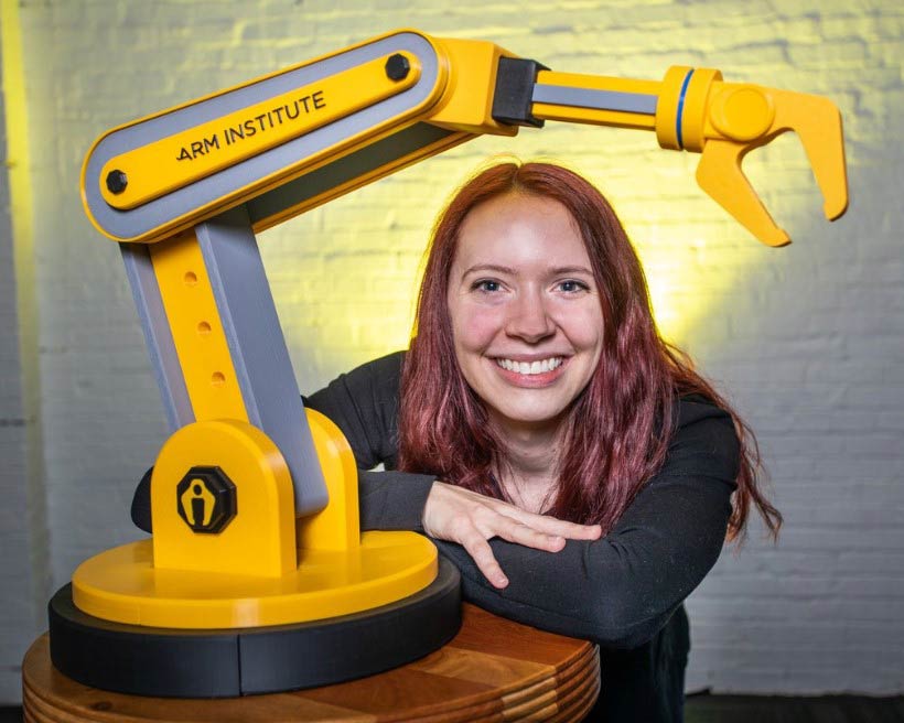 Photo of Livia Rice with ARM Institute logo-ed 3D printed robot arm