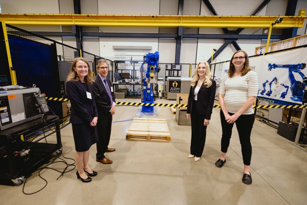 Four individuals stand in front of a robotic system