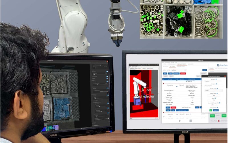Image of a man looking at a robot and a screen with code on it