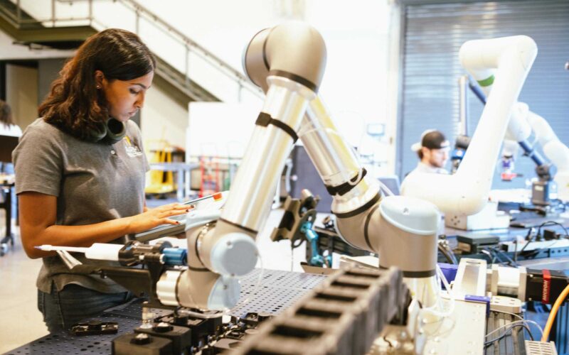 A woman works with a collaborative robot in a manufacturing lab
