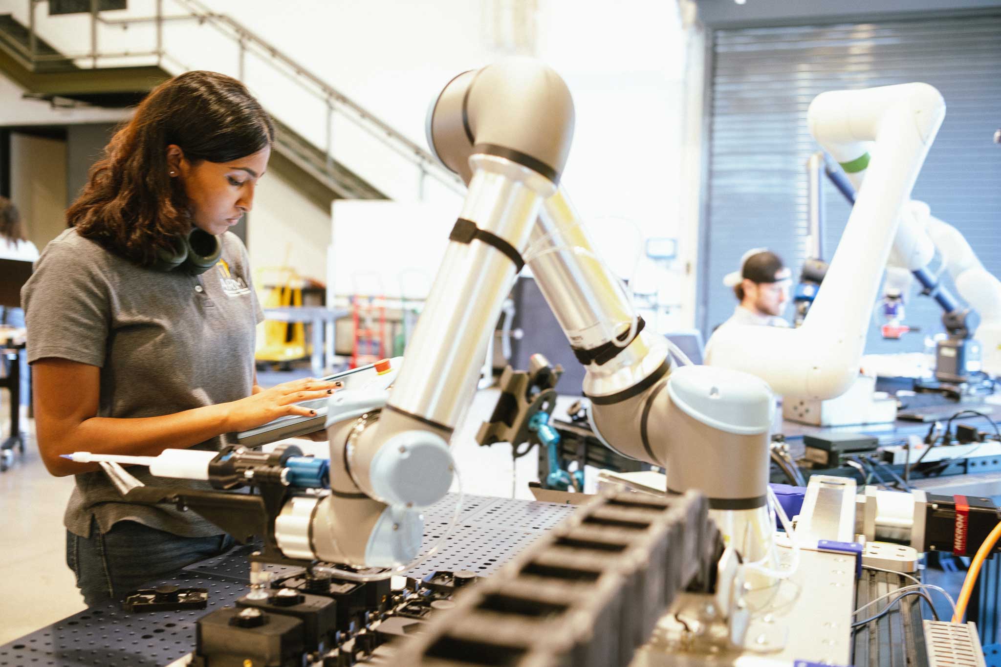 A woman works with a collaborative robot in a manufacturing lab