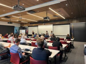 An image showing a panel discussion with people watching
