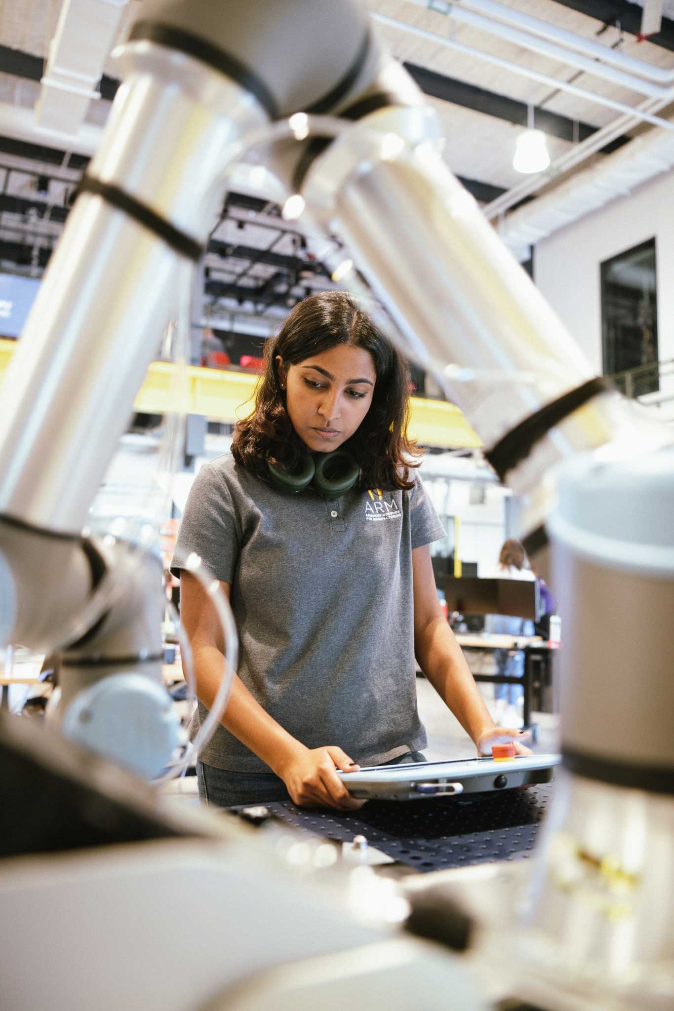 A woman uses a collaborative robot arm via a screen