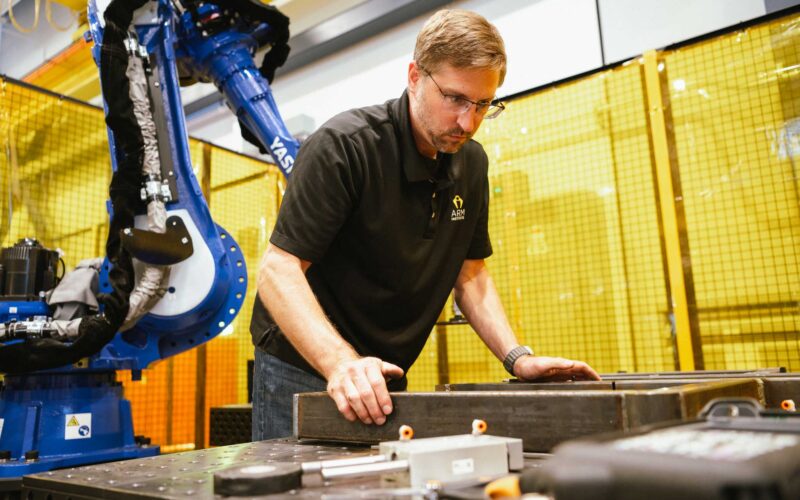 An engineer with a robot works on a manufacturing project