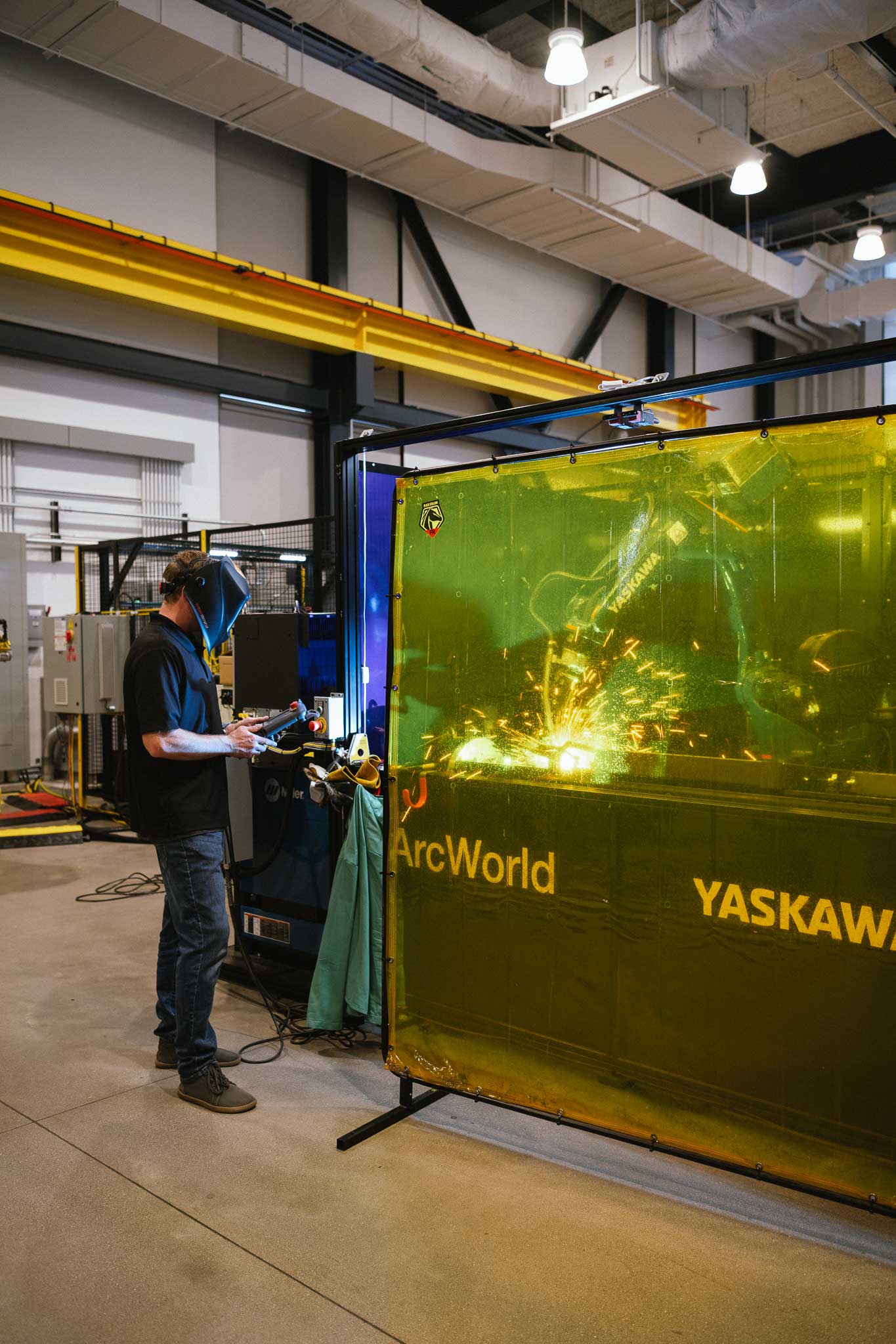 A man uses a tablet to complete robotic welding