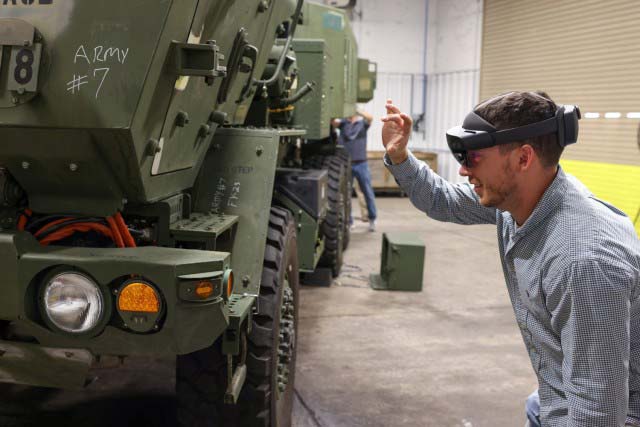 A person wearing an AR headset inspects an Army vehicle