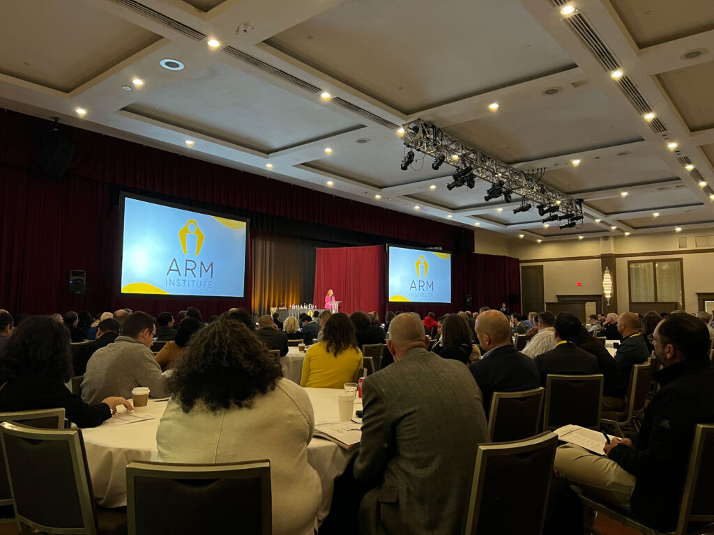 A woman presents on stage at the Annual Member Meeting